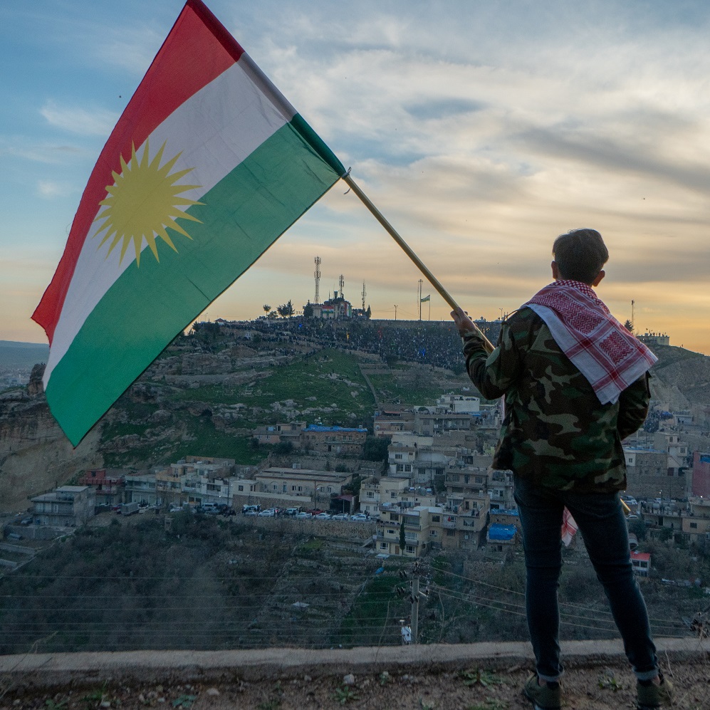 The boy is holding a Kurdistan flag